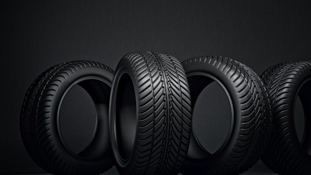 New tyres and worn tyres side by side on a car axle in a tyre shop, showing the importance of replacing tyres in pairs for safety and performance